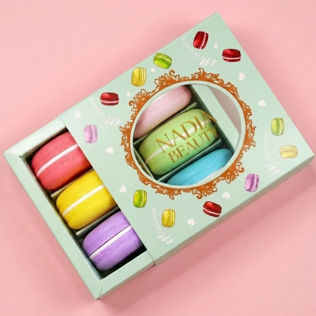 Colorful macaron-shaped lip balm set in a decorative box on a pink background