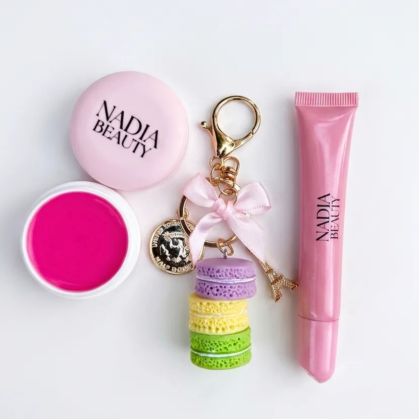 Nadia Beauty product set including a pink lip balm, colorful keychain, and pink tube on a white background.